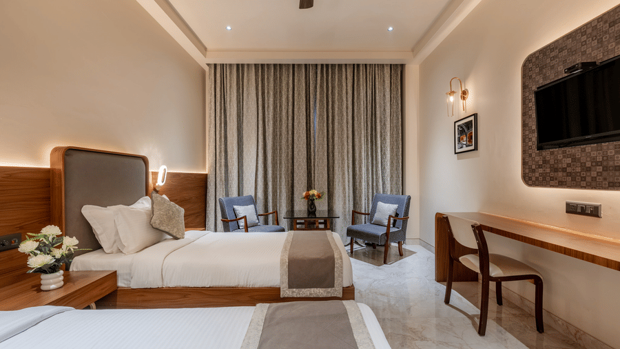 Spacious bedroom at Hotel Highway Prince, Behror, featuring a large bed, wooden furniture, and a large window overlooking the surrounding area.