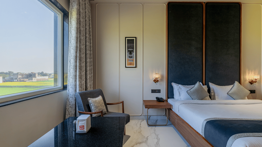  A bedroom with a king size bed, headboard panels, and a window overlooking a green landscape.