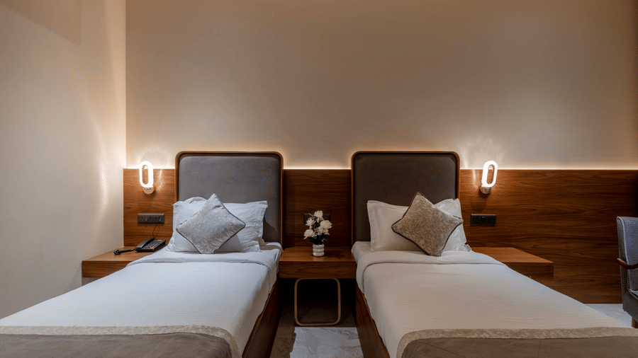 Superior twin room at Hotel Highway Prince, Behror with two separate beds, white linens, and bedside lamps against a wood-paneled wall.