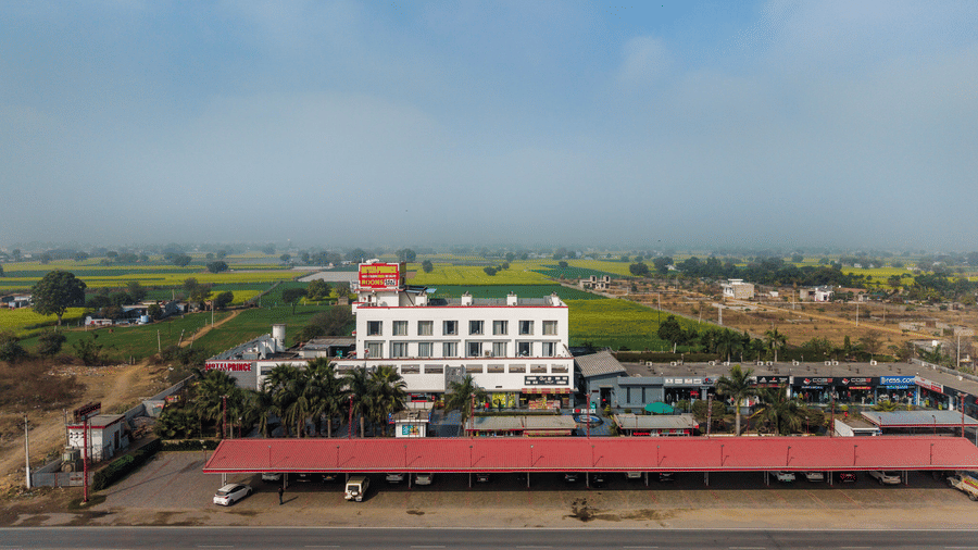 Hotel Highway Prince Paota wide aerial view with hotel building amid vast green agricultural fields and open countryside under overcast sky.