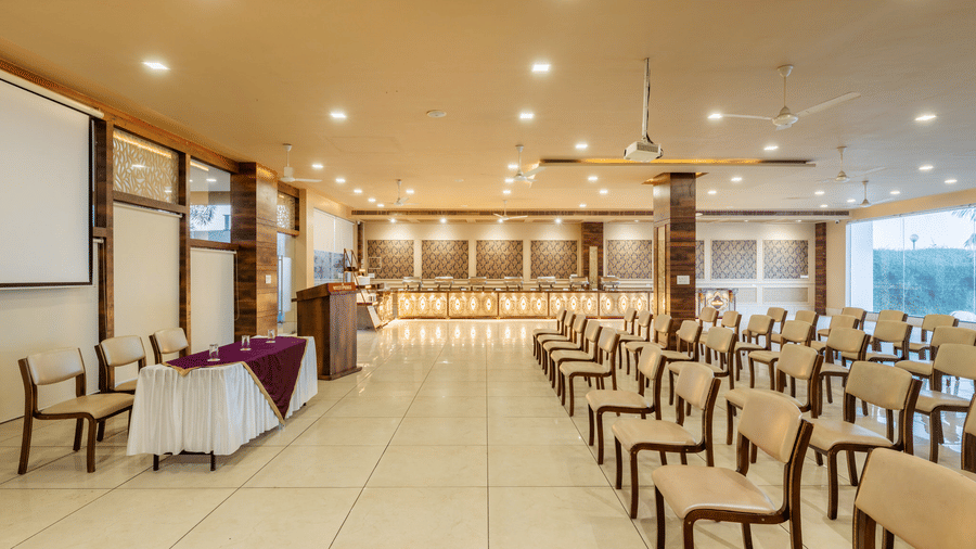 Hotel Highway Prince Paota fully arranged banquet hall with rows of white chairs, purple table draping, warm lighting, and large window views.
