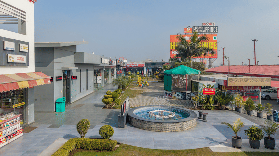 Hotel Highway Prince Paota aerial courtyard view with circular fountain, potted plants, yellow umbrella seating, and surrounding building wings.