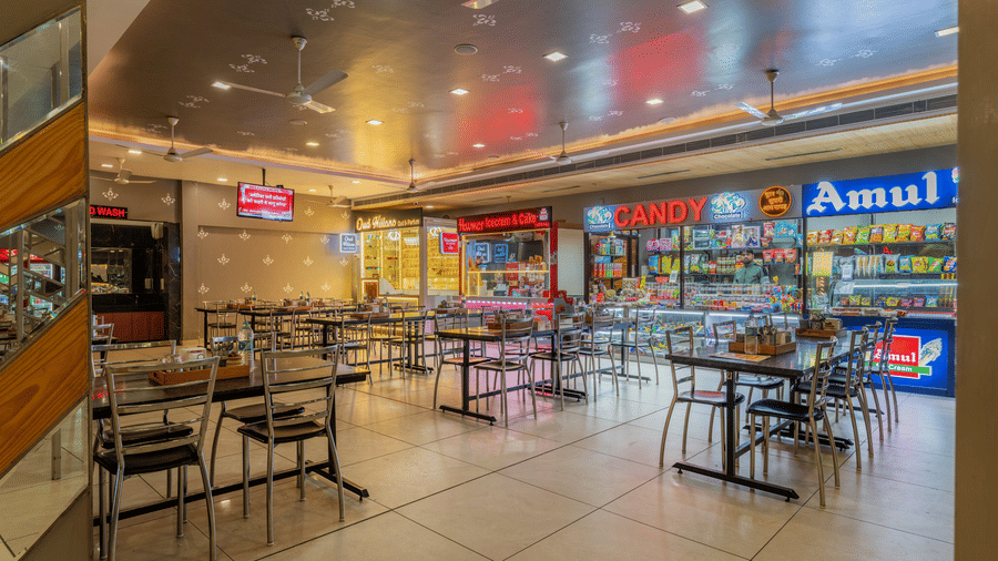 Hotel Highway Prince Paota food court featuring Amul branded counter, colourful signage, dining tables, black chairs, and bright interior lighting.