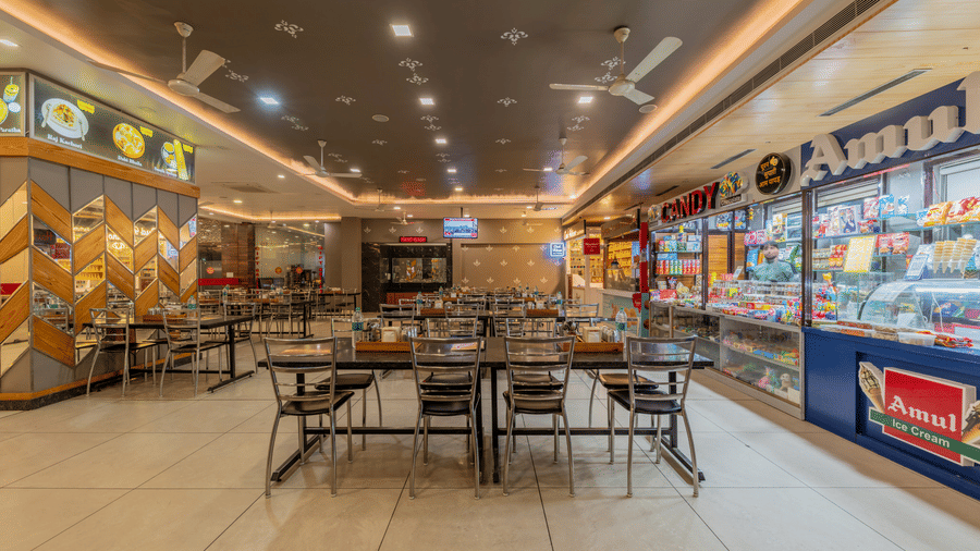 Hotel Highway Prince Paota food court counter area with display cabinets, branded stall signage, dining tables, and warm atmospheric lighting.