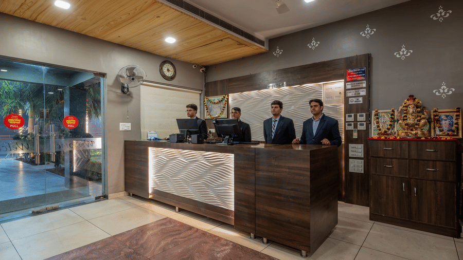 Hotel Highway Prince Paota reception lobby with marble check-in counter, uniformed staff, decorative artifacts, glass entrance, and recessed lighting.