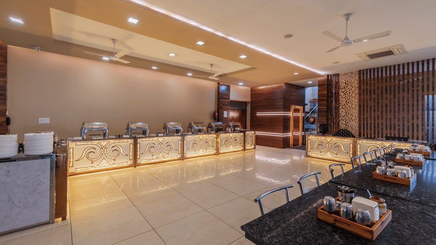 Hotel Highway Prince Paota restaurant with dark marble flooring, buffet service counter, dining tables, ceiling fans, and warm ambient lighting.