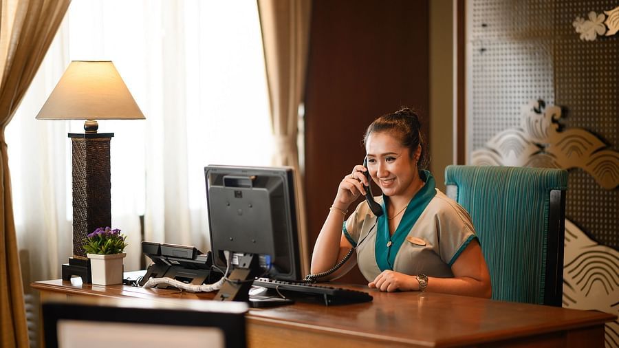 image of a receptionist attending to a call with a smile on her face - Maikhao Dream Villa Resort & Spa, Phuket