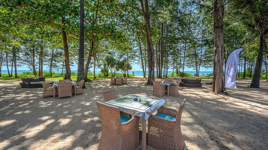Several dining tables scattered on the beach overlooking the lush green canopy in the background - Maikhao Dream Villa Resort & Spa, Phuket 
