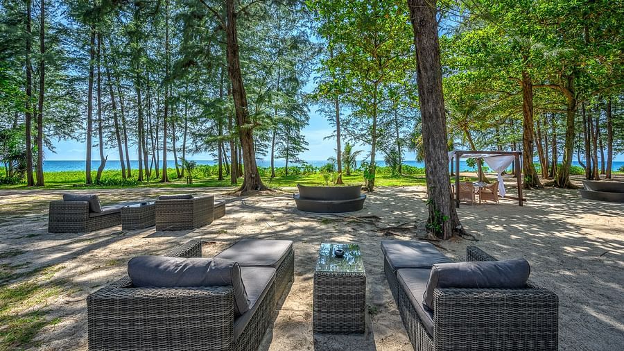 A well arranged dining area amidst tall green trees and a clear blue sky - Maikhao Dream Villa Resort & Spa, Phuket