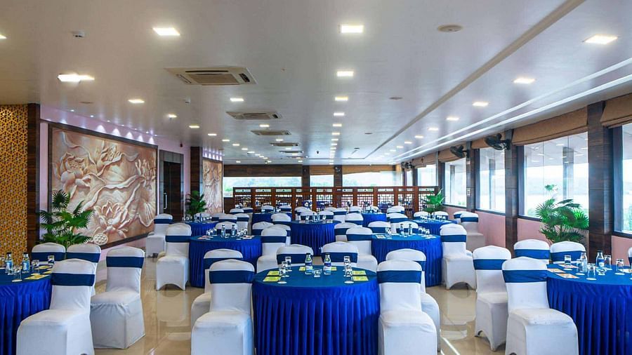 A large event room at Mansha Hotel Regency with round tables draped in blue and white tablecloths, and white chairs, arranged for a gathering.