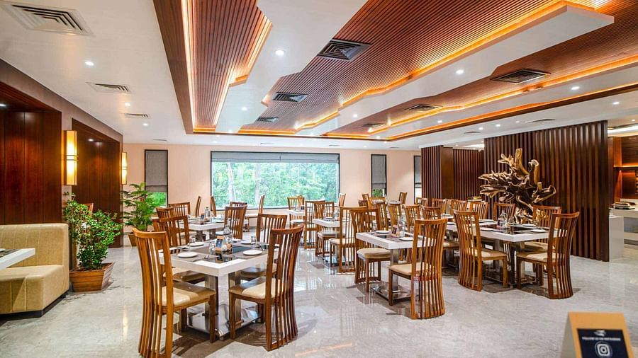 The warmly lit dining area of Pakeezah Restaurant at Mansha Palace features neatly set tables and comfortable wooden chairs.