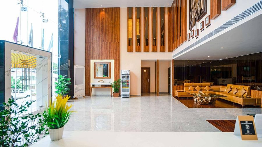 The bright and spacious lobby of Mansha Palace in Port Blair features elegant wooden accents and comfortable seating areas.