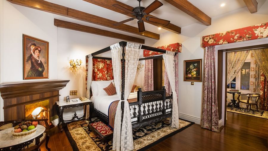 a plush bed and a fireplace by it - Mayfair Himalayan Spa Resort Kalimpong