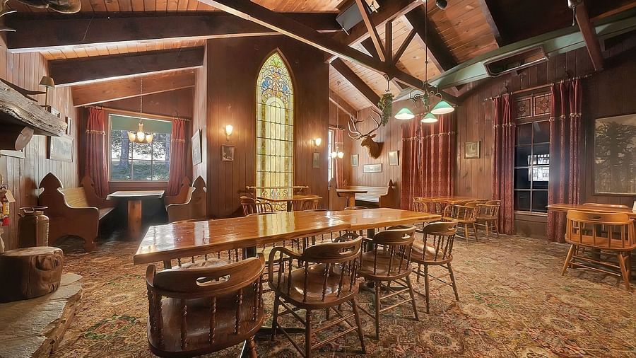A dining arrangement in the centre of a room with a carpet and large wooden beams - Narrow Gauge Inn - A Serenite Hotel Near Fish Camp.
