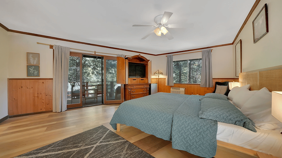 A view of a room at Narrow Gauge Inn with a double bed and sliding doors opening to a balcony.