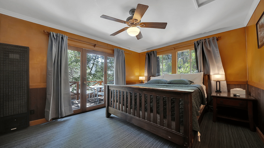 A view of a room at Narrow Gauge Inn with a double bed and sliding doors opening to a balcony.
