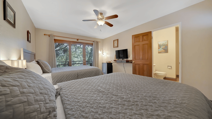 A view of a room at Narrow Gauge Inn with twin beds and a television.