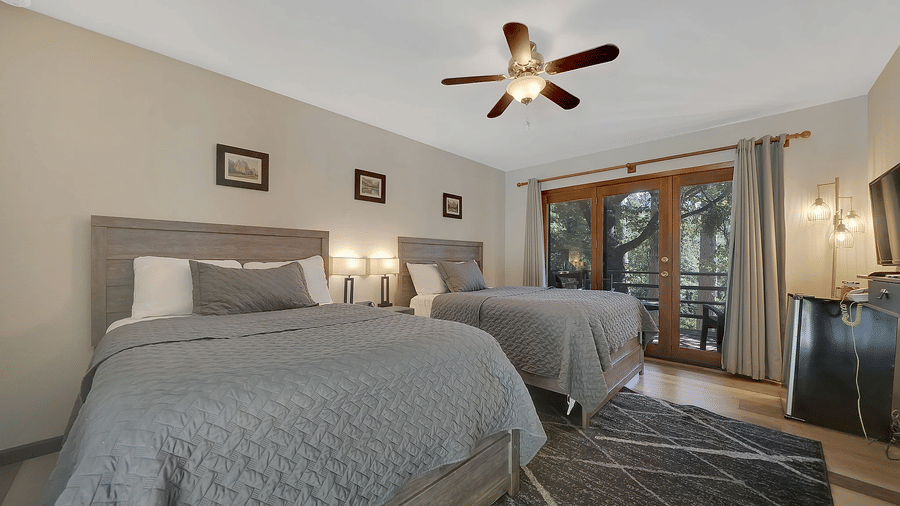 A view of a room at Narrow Gauge Inn with twin beds and sliding doors opening to a balcony.