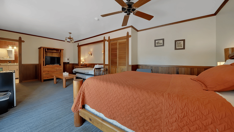 A view of a room at Narrow Gauge Inn with a double bed and a cabinet with a television.