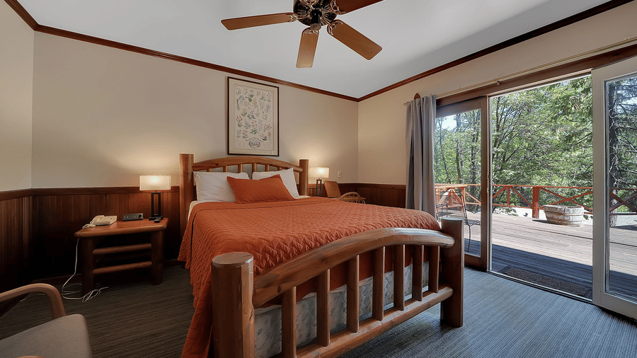 A view of a room at Narrow Gauge Inn with a double bed and sliding doors opening to a balcony.