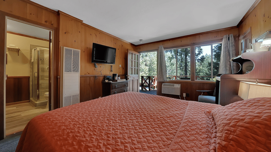 A view of a room at Narrow Gauge Inn with a double bed and sliding doors opening to a balcony.