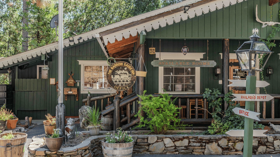 Exteriors of a pastel green cabin with potted plants placed outside the entrance - Narrow Gauge Inn - A Serenite Hotel Near Fish Camp.