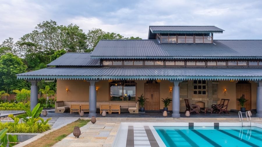 Restaurant view at Rhino and River BluSalzz Collection, Pobitora featuring the pool, green trees, and clear blue sky.