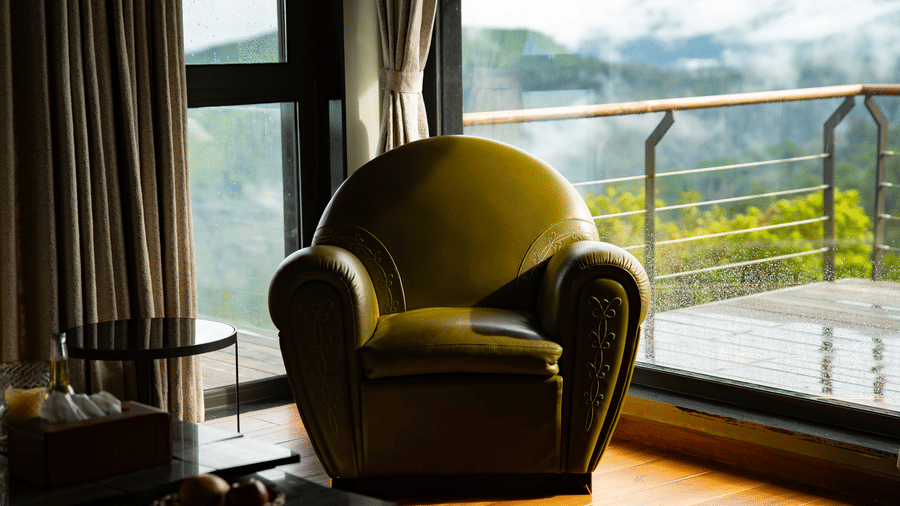 A plush green armchair sits in a room at Stanley Revelation, with a stunning mountain view from the window.