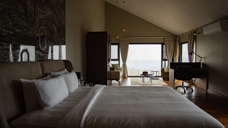 A room at Stanley Leisure with a double bed, a wardrobe, a work desk and chair and French doors opening to a foggy view.