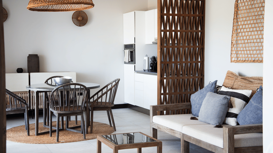 A living area with a sofa with pillows, a tea table and a dining area at Tamarind Hills Resort and Villas, Antigua.