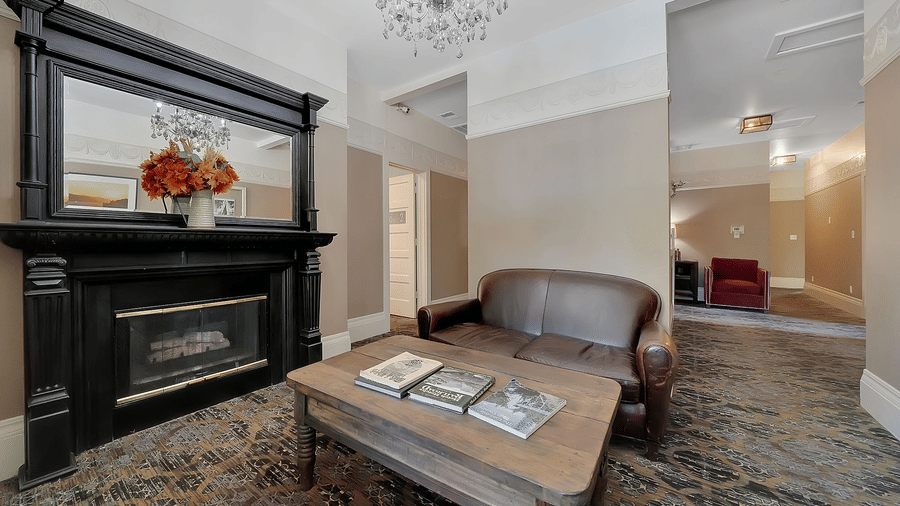 A living room area of a suite at The Groveland Hotel with a sofa and a coffee table beside the fireplace | Yosemite Lodging Groveland