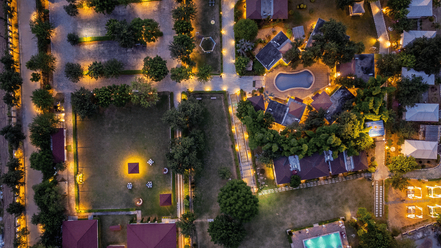 Aerial night view of lamp-lit pathways and cottages at Valley by Grassfield, a resort in Jaipur.