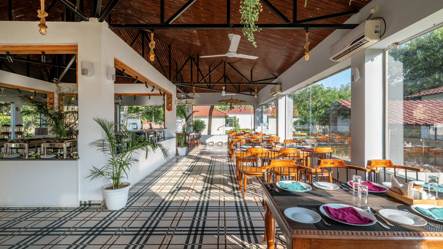 Dining room with wooden furniture and chequered floor at Valley by Grassfield, a resort in Jaipur.