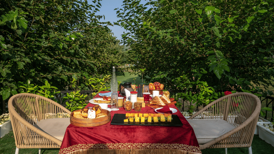 Outdoor dining table spread with dishes at Valley by Grassfield, a resort in Jaipur.