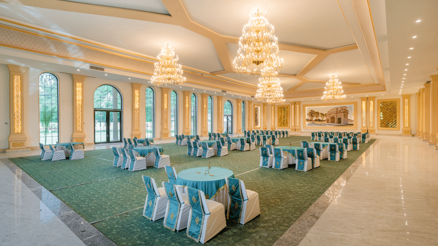 Banquet tables by tall windows in The Royal Knot hall at Valley by Grassfield, a destination wedding resort in Jaipur.