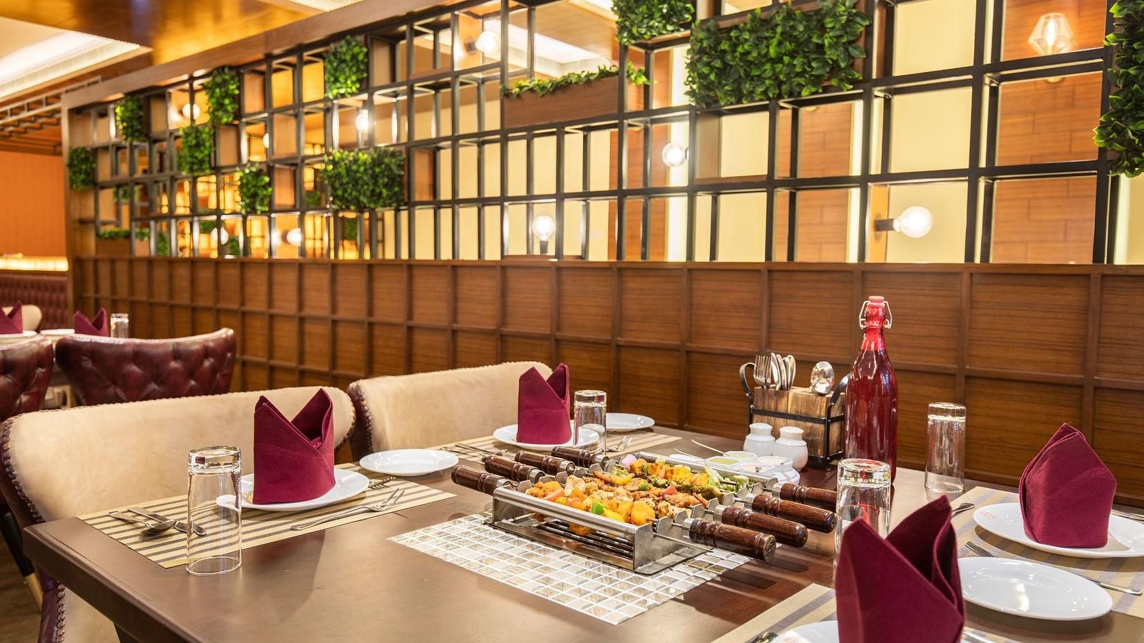 An indoor restaurant setting with tables set for dining, featuring modern decor and a vertical garden wall.
