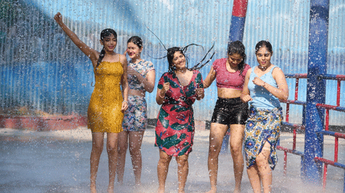 Group of women enjoying a splash zone under mist and water sprays at a water park.