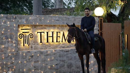 An exterior view of the themis farm house and a horse man standing at the entrance. 