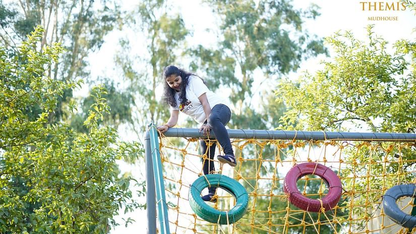 a woman walking on a commando net at Themis Mudhouse - A Nature's Retreat Resort & Wellness