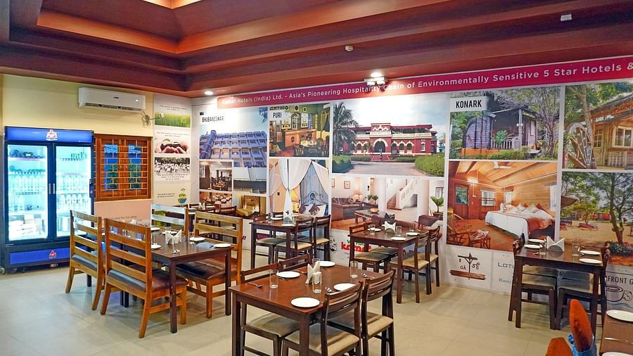 Colourful indoor seating area of Vithal Kamat restaurant with food posters and wooden tables