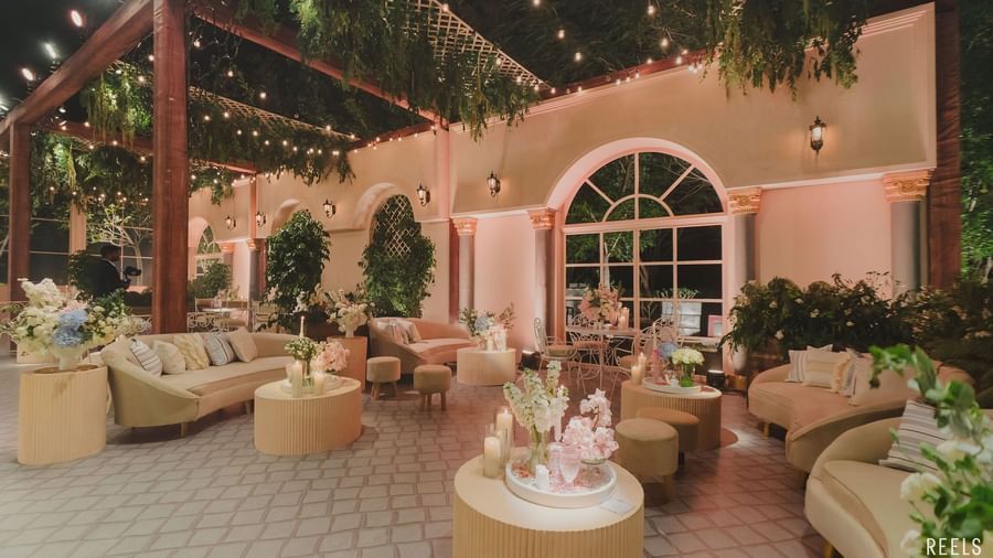 Outdoor lounge seating area decorated with warm lighting and floral arrangements for an elegant evening event.