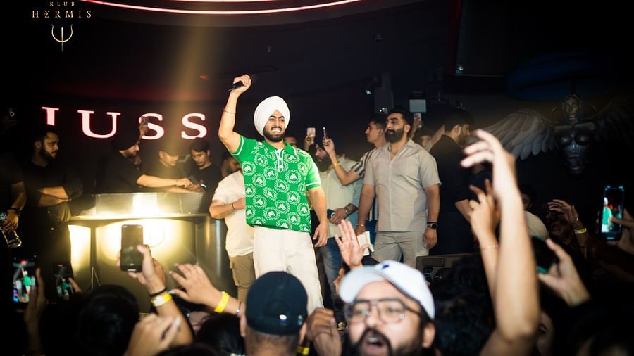 A Dj performing on stage with a cheering crowd.