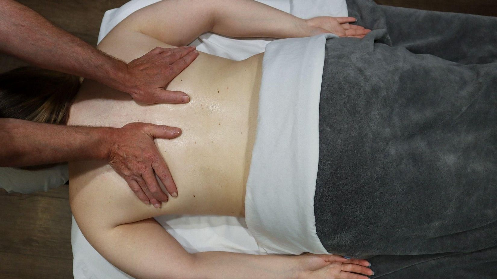 Person receiving a therapeutic back massage with warm oil, lying face down on a treatment table at YO1 Longevity and Health Resorts