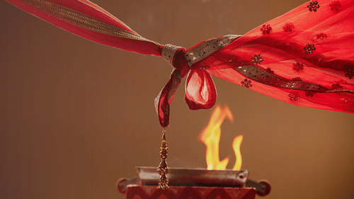 A knot tied by two design fabric pieces above the fire implicating a wedding ceremony that is taking place.