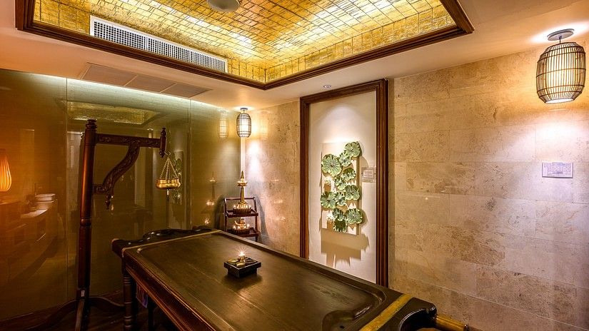 corner view image of the maikhao dream spa with a wooden bed in the middle and door in the corner of the room