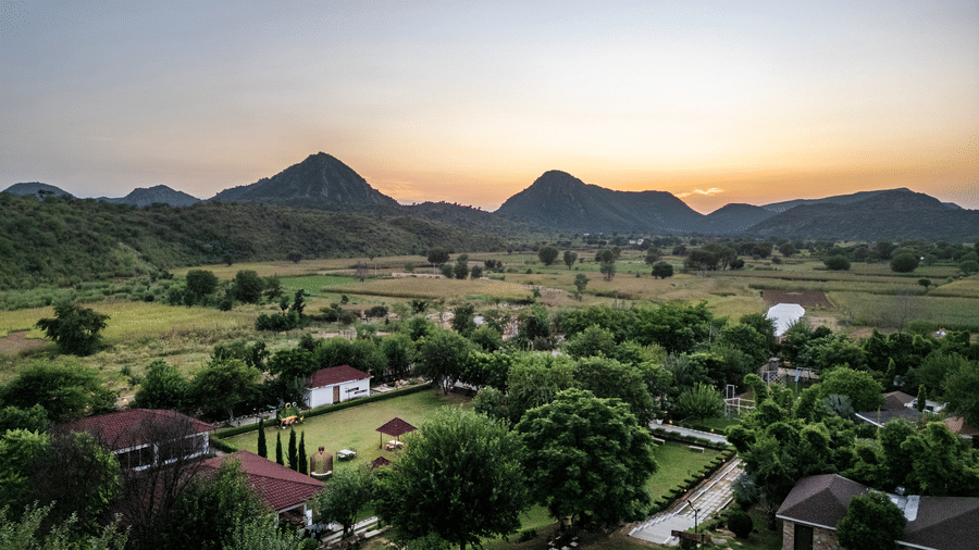 Aerial view of cottages nestled in greenery at Valley by Grassfield, a resort near the Aravalli hills in Jaipur.