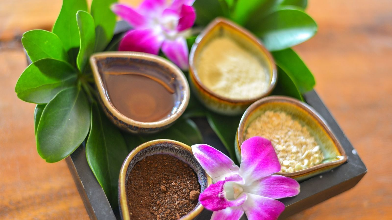A container with four bowls holding various elements for the spa decorated with flowers - Maikhao Dream Villa Resort & Spa, Phuket