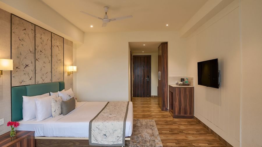 Superior Room at Voyage Milestone Hotel and Banquet with double bed, warm lighting, and rustic wood flooring for a homely feel.