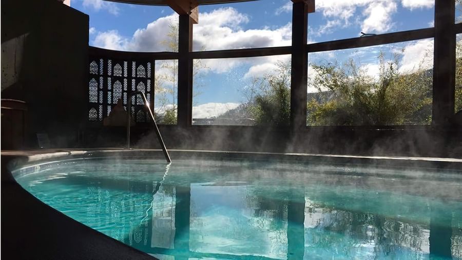 The Tallman Hotel's inviting indoor pool with steam rising and large windows offering scenic views.