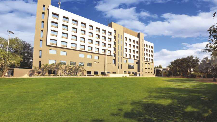 Exterior view of hotel building with expansive lawn – Narayani Heights Hotel & Resorts